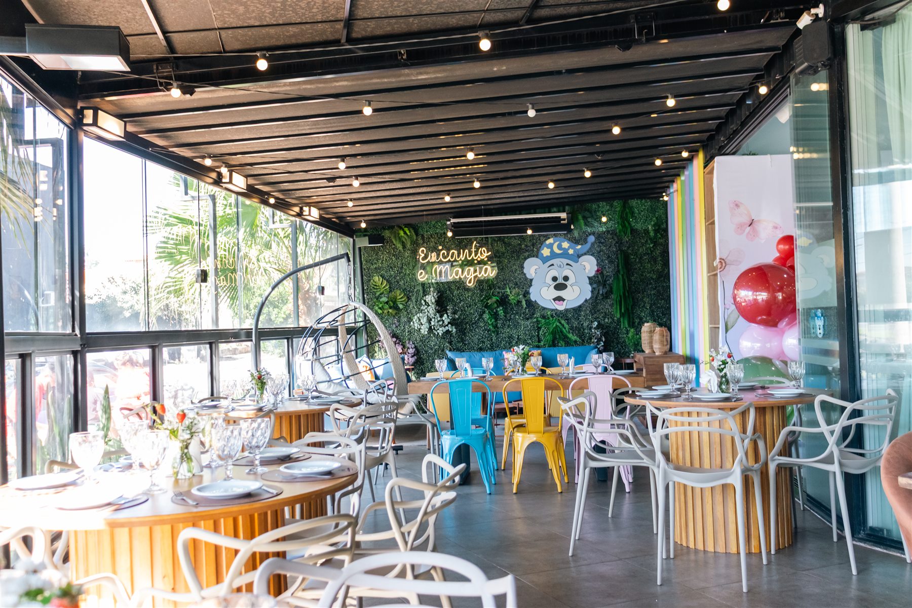 Salão decorado do Encanto e Magia com letreiro de neon e mural do mascote
